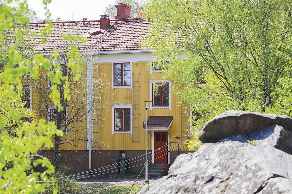 Keltainen puutalo, jossa punaiset ovet, ikkunat sekä katto.