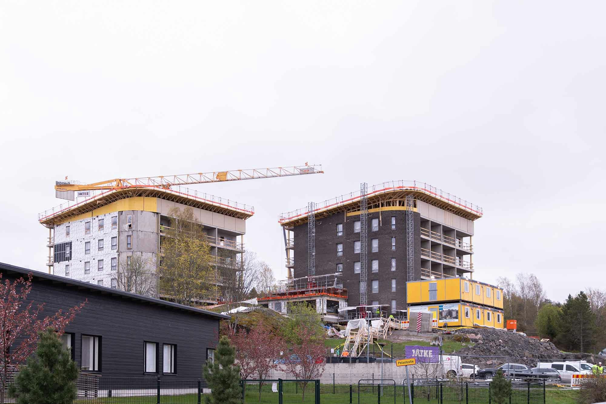 Kaksi rakenteilla olevaa kerrostaloa, joiden takana on keltainen torninosturi.