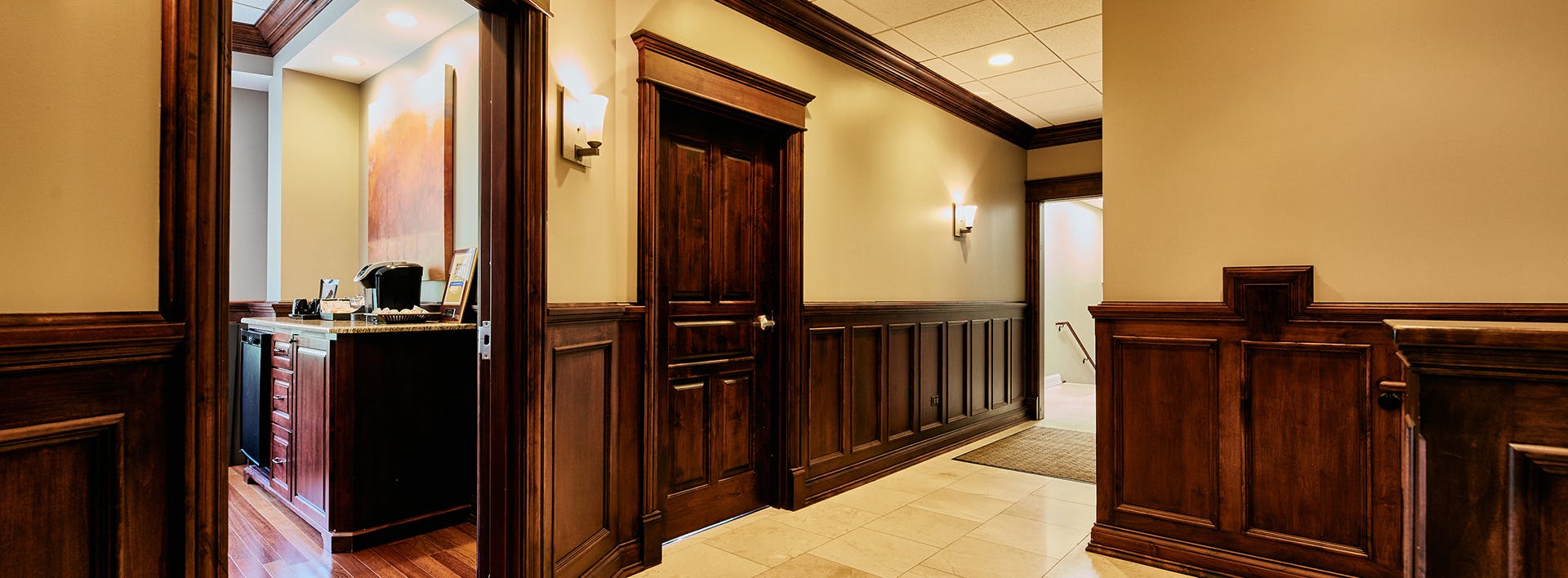 there is a hallway with a wooden paneled wall and a white tiled floor