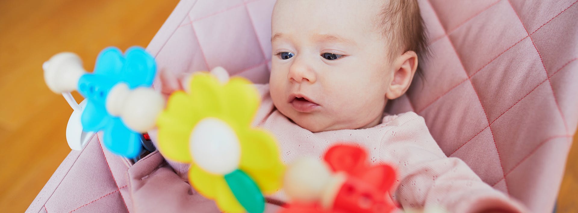 there is a baby in a pink chair holding a toy