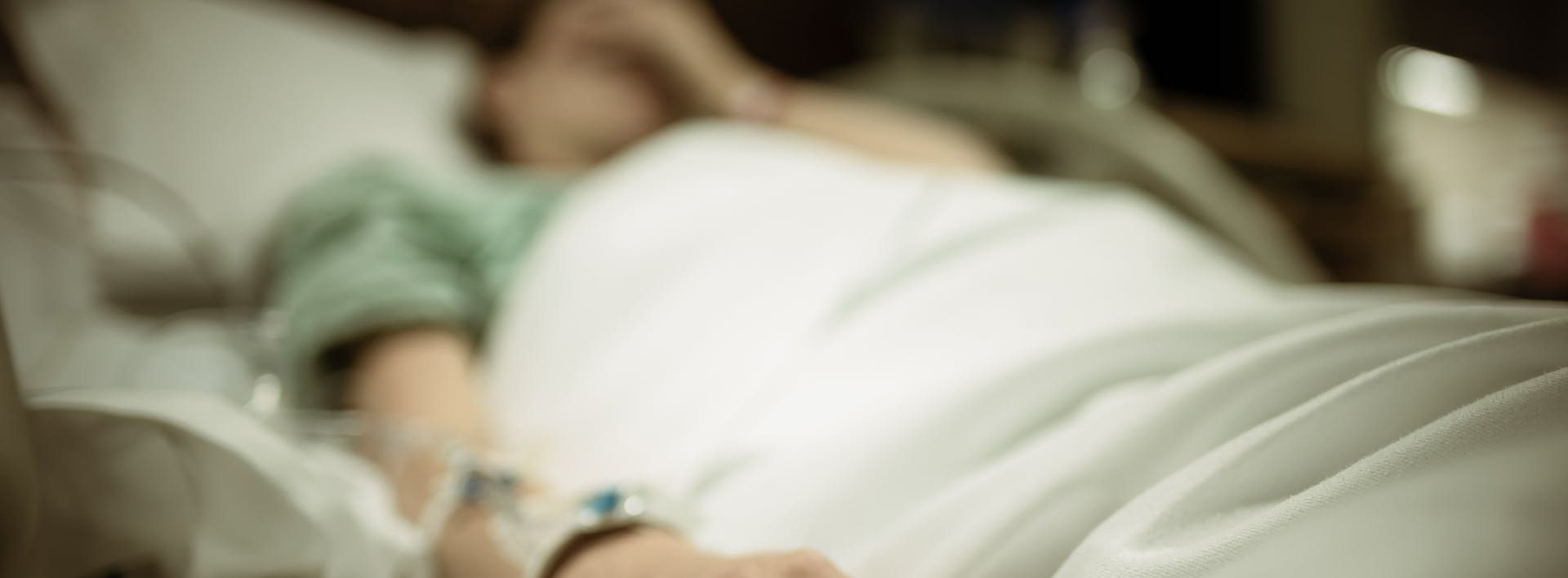 someone is laying in a hospital bed with a drip in their hand