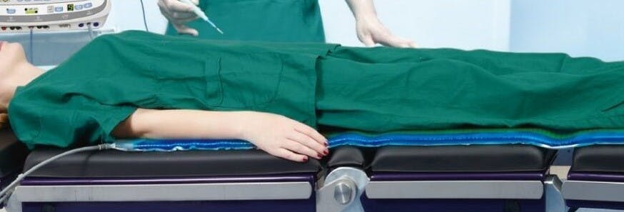 there is a woman laying on a hospital bed with a nurse in the background