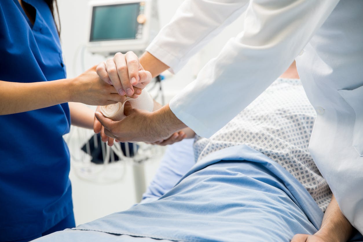 Person in a hospital bed getting their arm wrapped