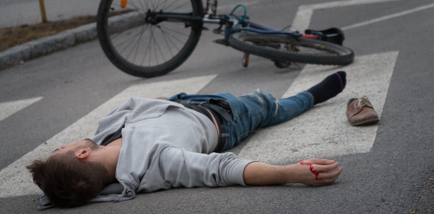 A man laying on the street after falling off his bike