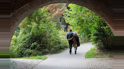 Couple walking in a park under a bridge