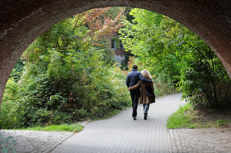 Couple walking in a park under a bridge