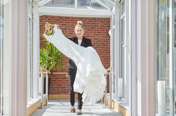 Laura carrying a wedding dress to a bedroom