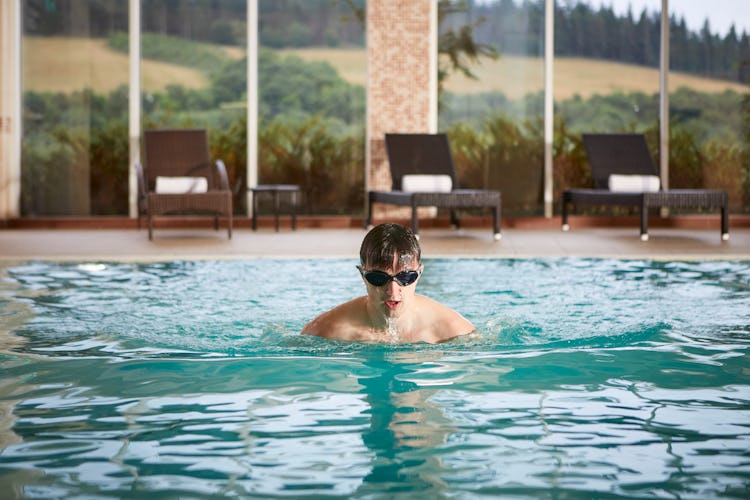 Man swimming in the pool at Cardrona with views over the Tweed Valley