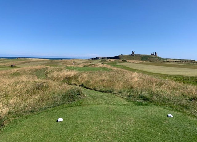 Blue skies over Dunstanburgh Links golf course with the castle in the distance