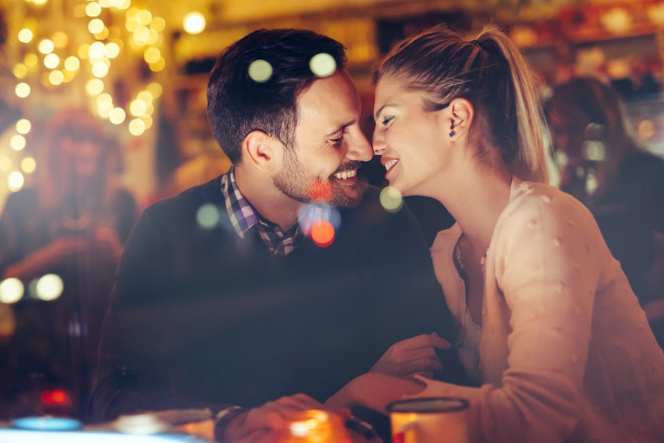A man and a woman enjoy a tender moment in a hotel bar decorated with fairy lights
