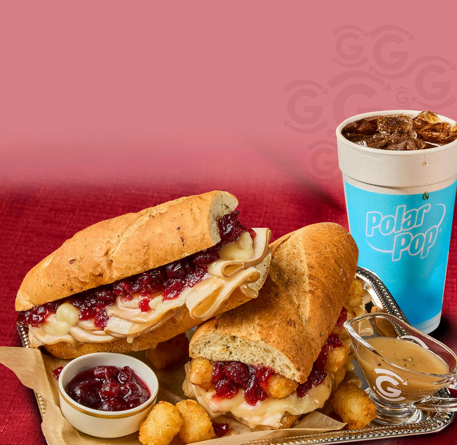 Two turkey and cranberry sandwiches topped with melted cheese and served with tater tots, cranberry sauce, gravy, and a Polar Pop fountain drink.