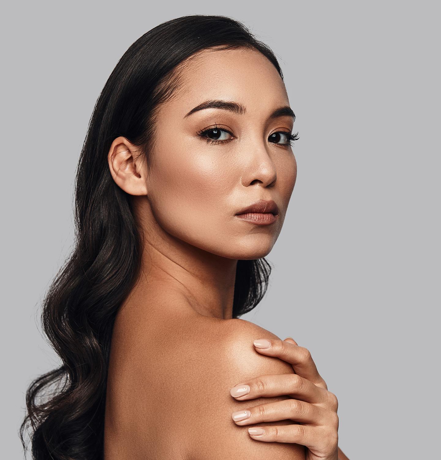 woman with long black hair and a tan top