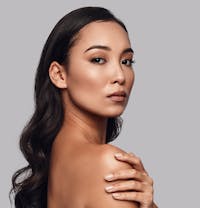 woman with long black hair and a tan top