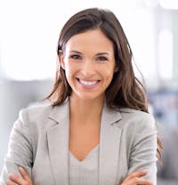 smiling woman in business suit with arms crossed in front of her