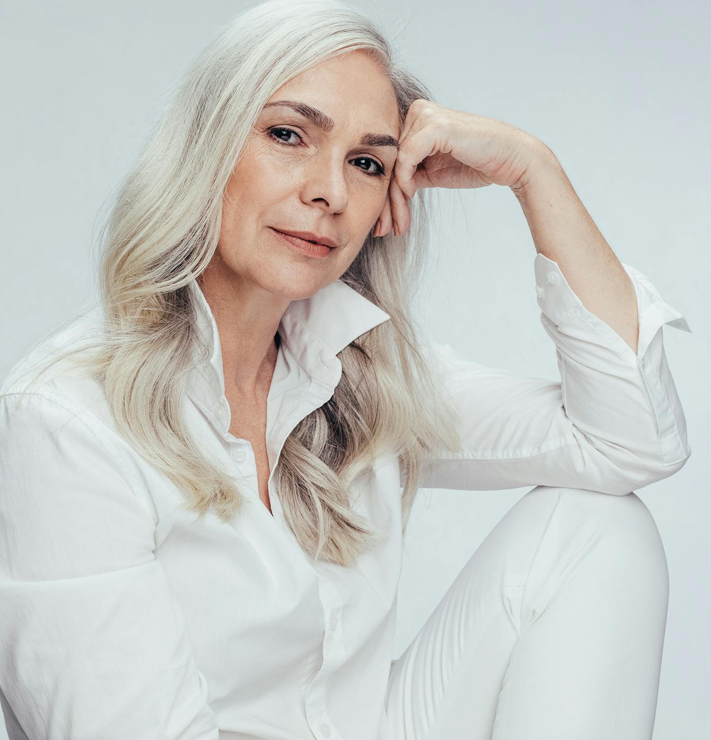 blond woman with white shirt and white pants sitting on a chair