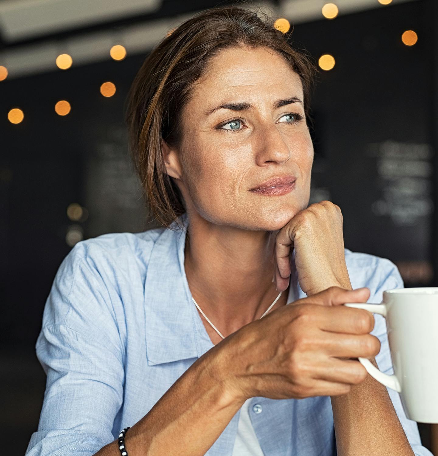 woman sitting at a table with a cup of coffee in her hand