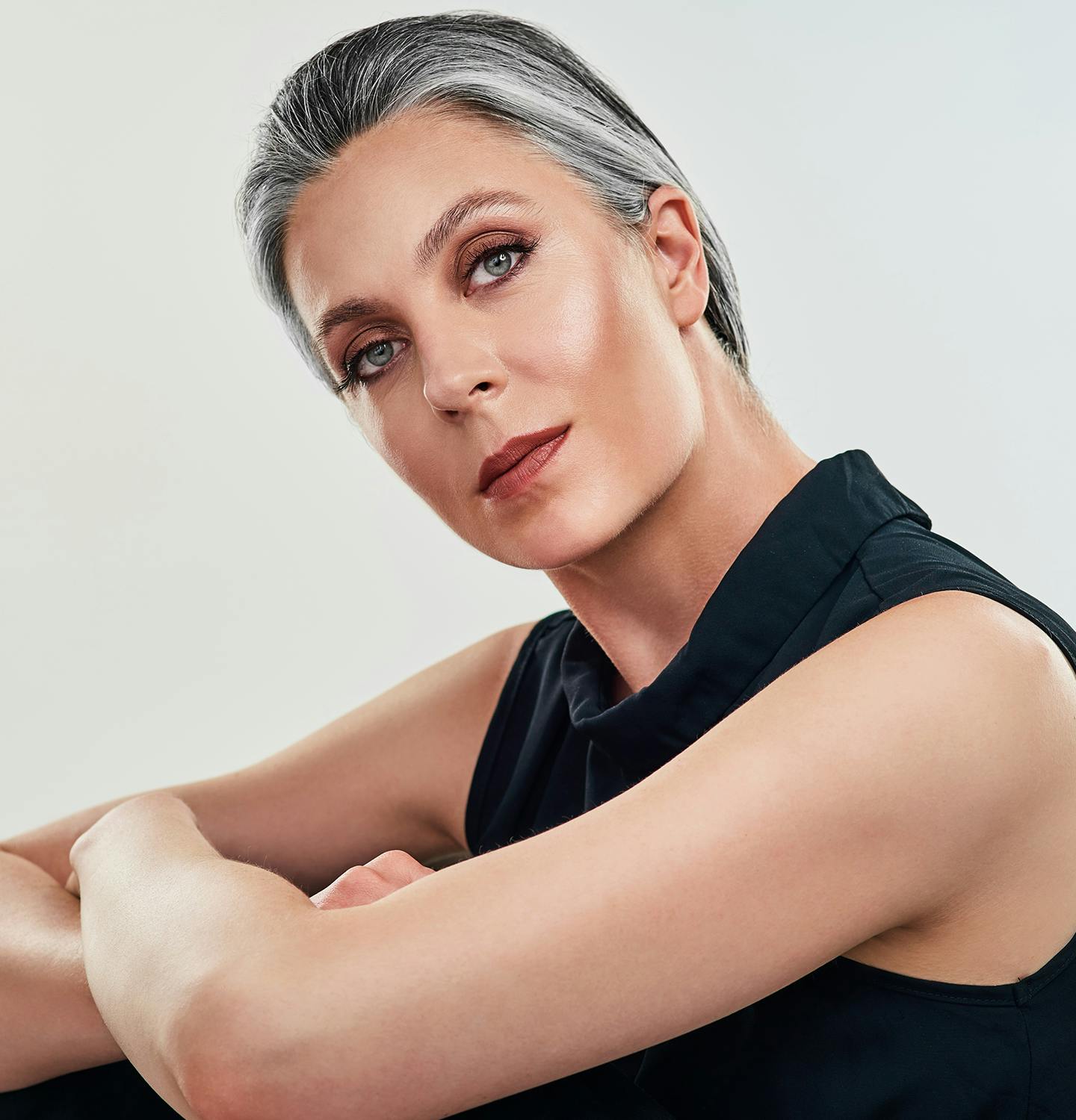 blond woman with short hair and a tan top posing for a picture