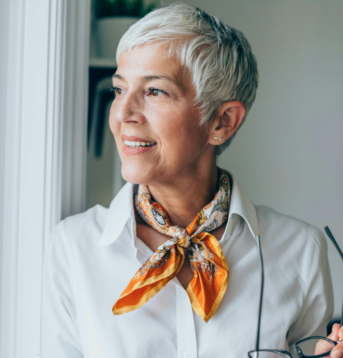 there is a woman with a scarf and glasses looking out a window