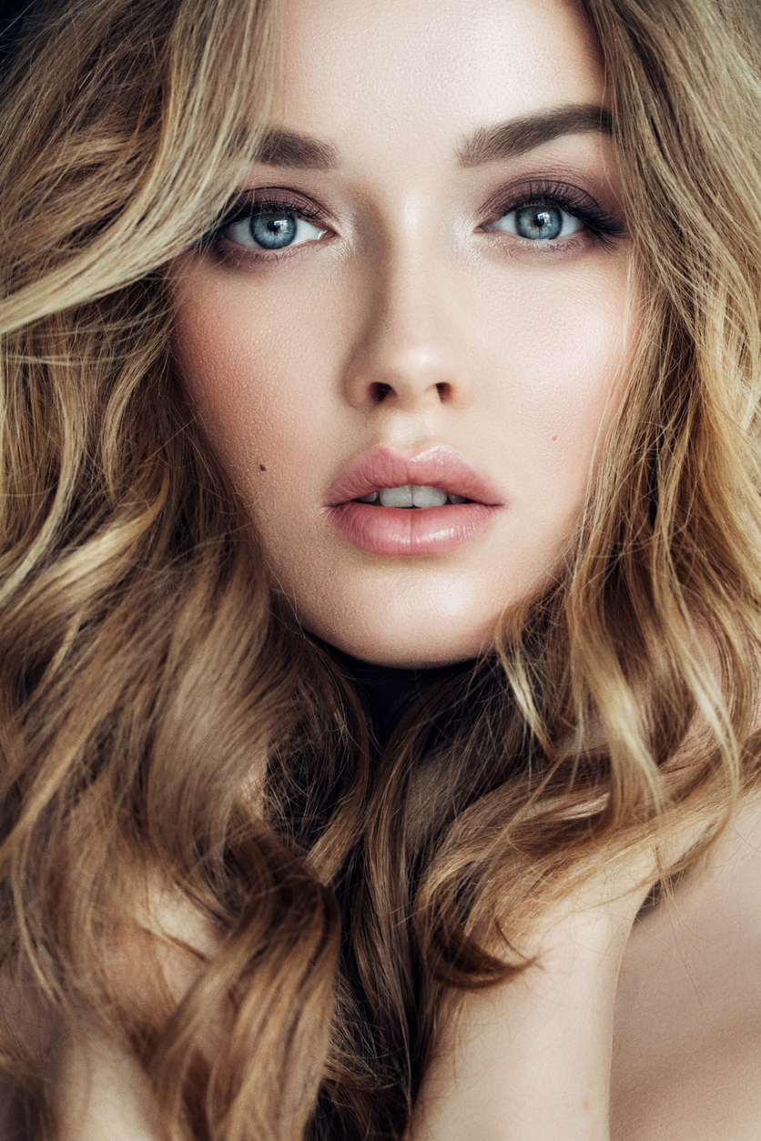 close up of blond woman's face holding hands on neck
