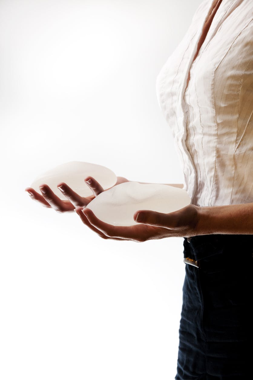 woman holding breast implants in each hand