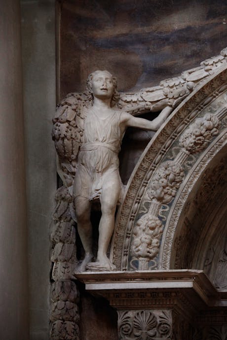 Desiderio da Settignano, “Putto reggi-festone”, particolare della “Tomba monumentale di Carlo Marsuppini”, 1454-1459, marmo e affresco. Firenze, Santa Croce, navata sinistra 