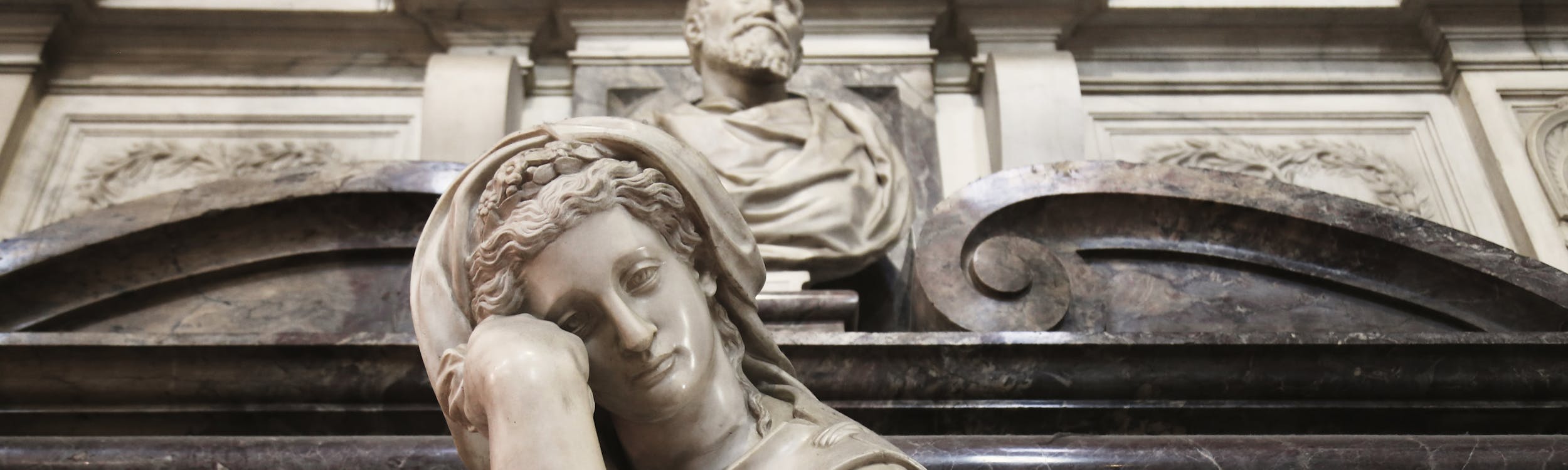 Giorgio Vasari: progetto; Battista Lorenzi: “Busto di Michelangelo”, “Pittura”; Valerio Cioli: “Scultura”; Giovanni Bandini detto Giovanni dell’Opera: “Architettura”; Giovan Battista Naldini: “Pietà e angeli reggicortina”, “Tomba monumentale di Michelangelo Buonarroti”, particolare, 1564-1576, marmo e affresco. Firenze, Santa Croce, navata destra Giorgio Vasari: progetto; Battista Lorenzi: “Busto di Michelangelo”, “Pittura”; Valerio Cioli: “Scultura”; Giovanni Bandini detto Giovanni dell’Opera: “Architettura”; Giovan Battista Naldini: “Pietà e angeli reggicortina”, “Tomba monumentale di Michelangelo Buonarroti”, particolare, 1564-1576, marmo e affresco. Firenze, Santa Croce, navata destra