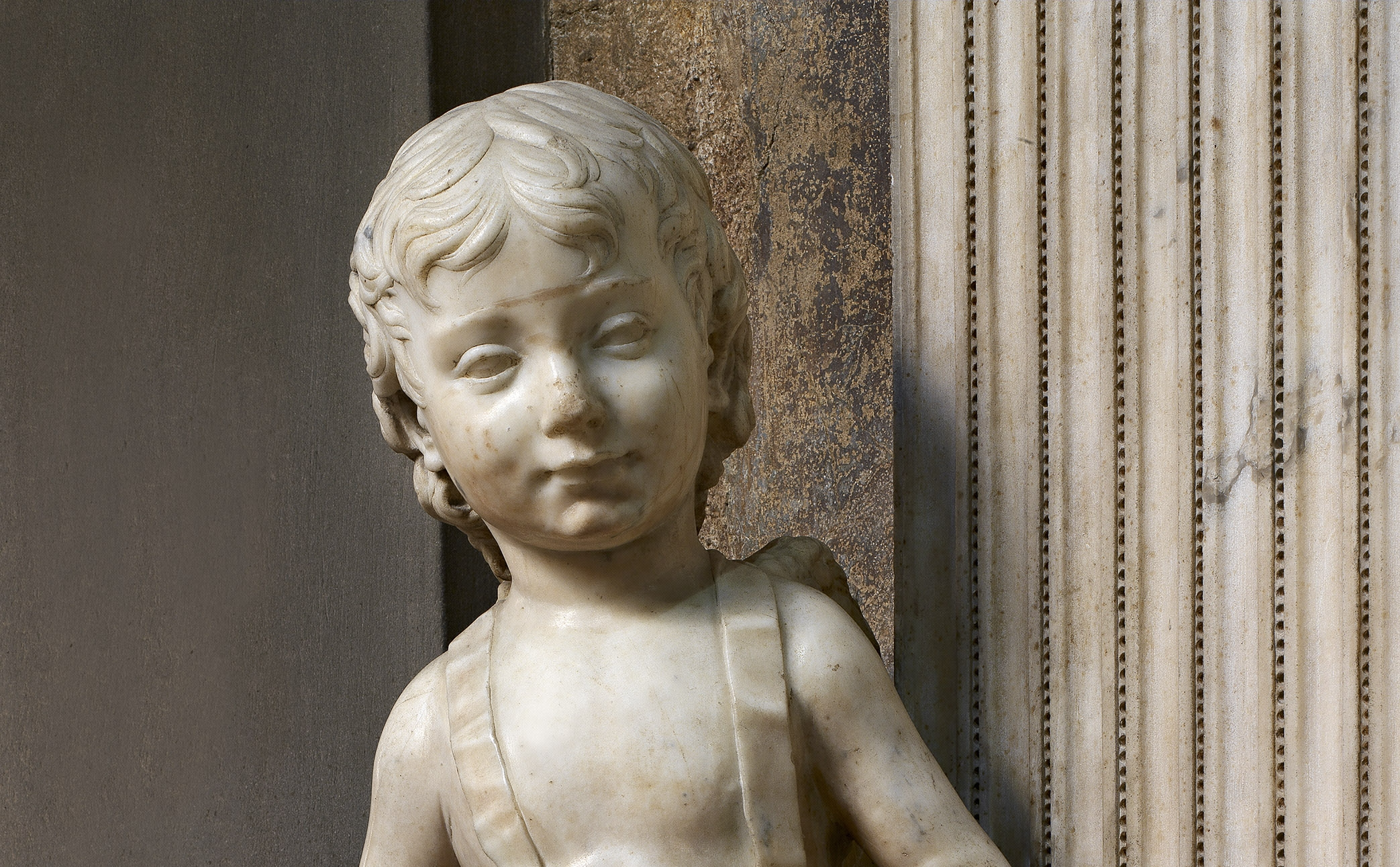Desiderio da Settignano, “Putto reggi-scudo”, particolare della “Tomba monumentale di Carlo Marsuppini”, 1454-1459, marmo e affresco. Firenze, Santa Croce, navata sinistra