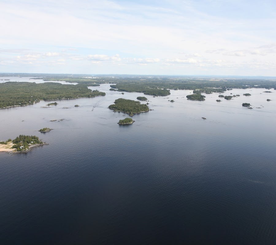 La vue érienne du lac Saint-Jean est impressionante ! L'eau semble calme, des îles peuplées d'arbres et de plages sabloneuses alimentent le paysage à perte de vue. Le ciel est clair avec quelques nuages blancs. La nature et la sensation de grandeur du lac Saint-Jean est saisissante. The aerial view of Lake Saint-Jean is impressive! The water seems calm, islands populated with trees and sandy beaches fill the landscape as far as the eye can see. The sky is clear with a few white clouds. The nature and feeling of grandeur of Lake Saint-Jean is striking.