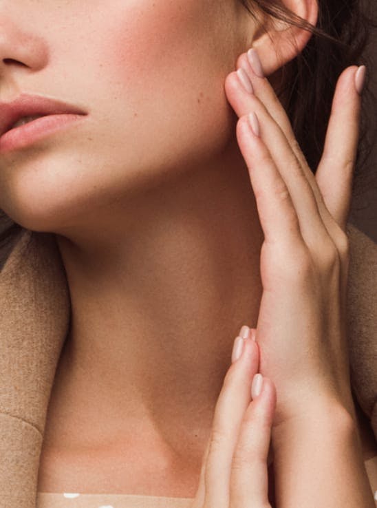 Woman's hands touching her jaw line and beautiful neck.