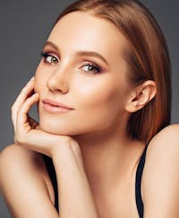 Smiling woman with her chin resting on her hand.