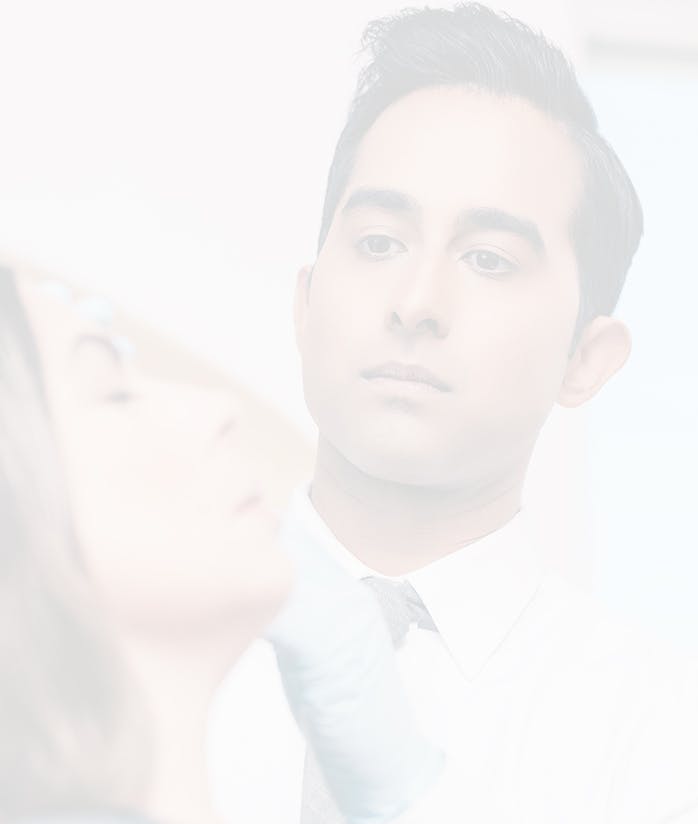 Blurred background image of Dr. Nik Rana examining a patient.