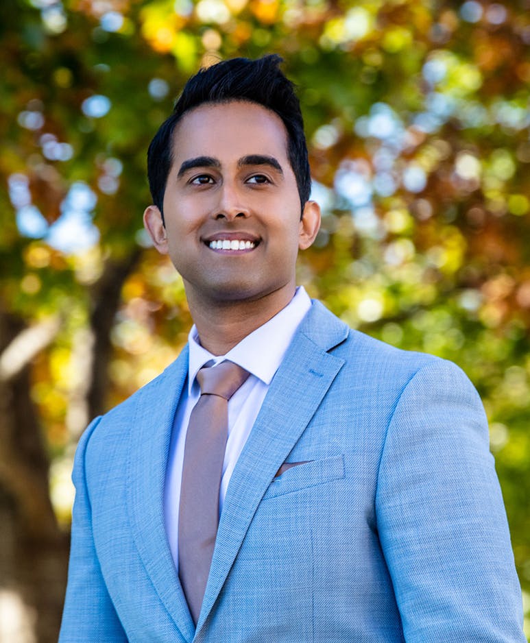 Plastic Surgeon Dr. Nik Rana with foliage in background.