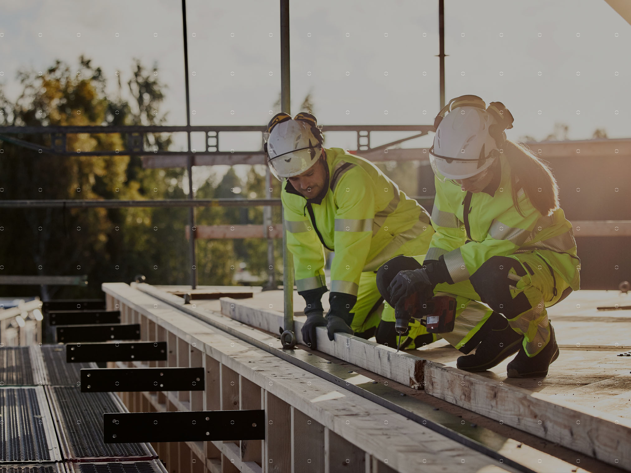 Professional users wearing high-visibility workwear and helmets while working on a construction site.