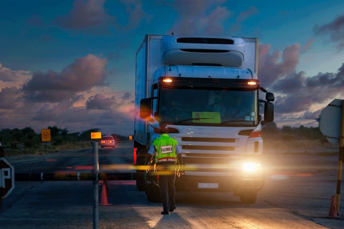 Homme en gilet jaune debout devant un camion de nuit