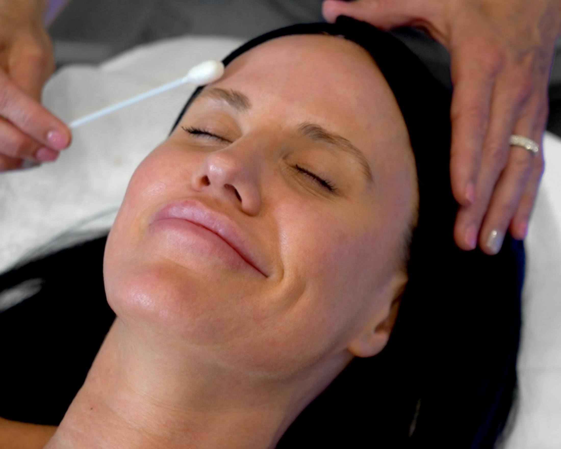 Woman with black hair receiving a skin treatmeant.