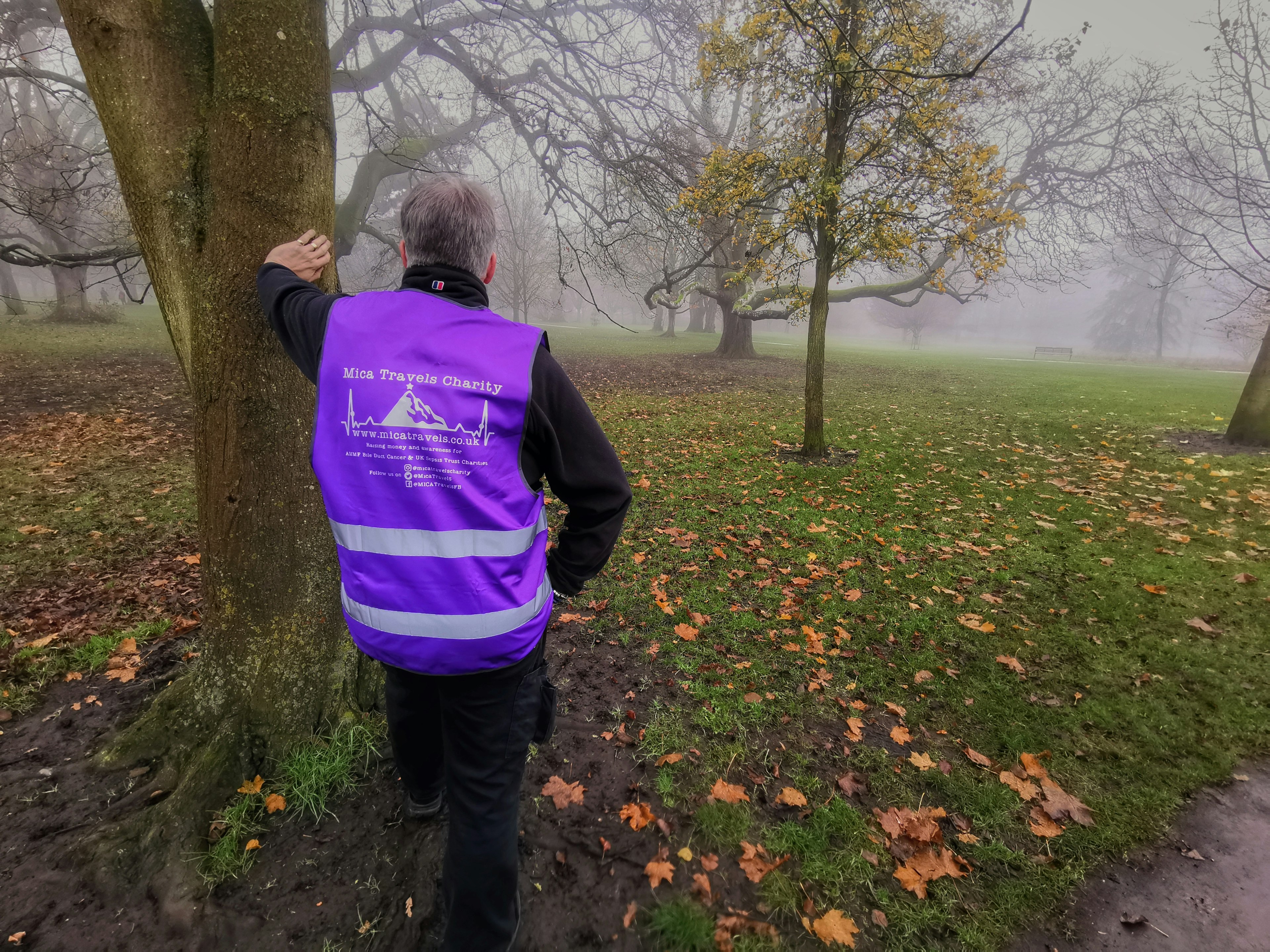 Mike leaning against a tree wearing a purple Mica Travels reflective vest
