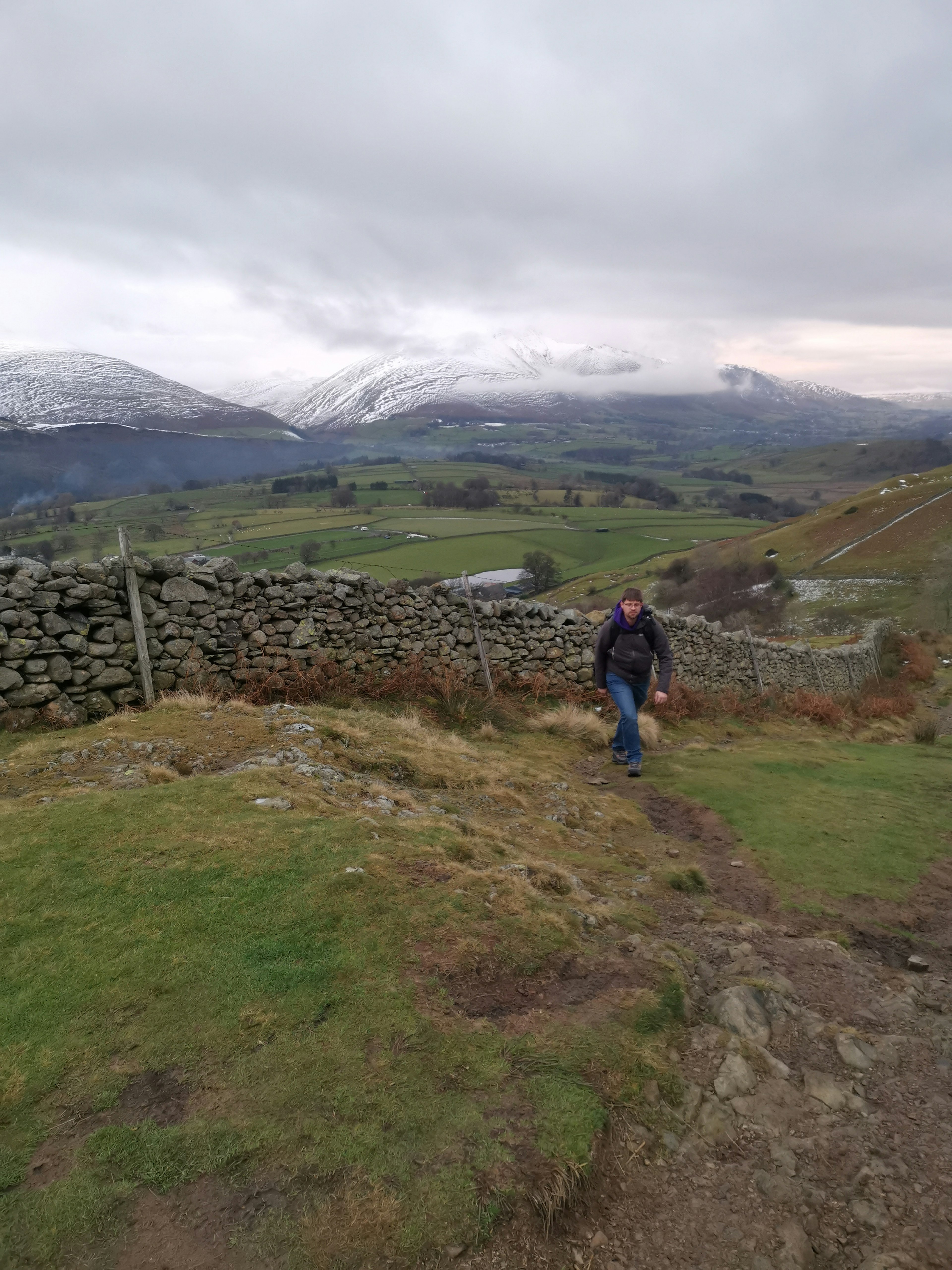 Pete walking up a hill with mountains in the background
