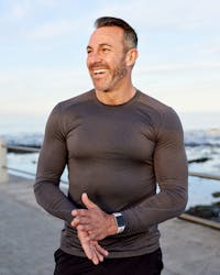 A middle aged man standing on a bridge above the sea and smiling after getting anti-aging therapy in Tampa.