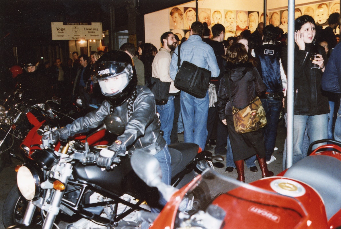 Audiences attend Simone LeAmon, MOTO Showroom, with performance riders from the Moto Guzzi motorcycle club, presented at Gertrude Contemporary Art Spaces, 2003. Courtesy of the artist and the Gertrude Archive.