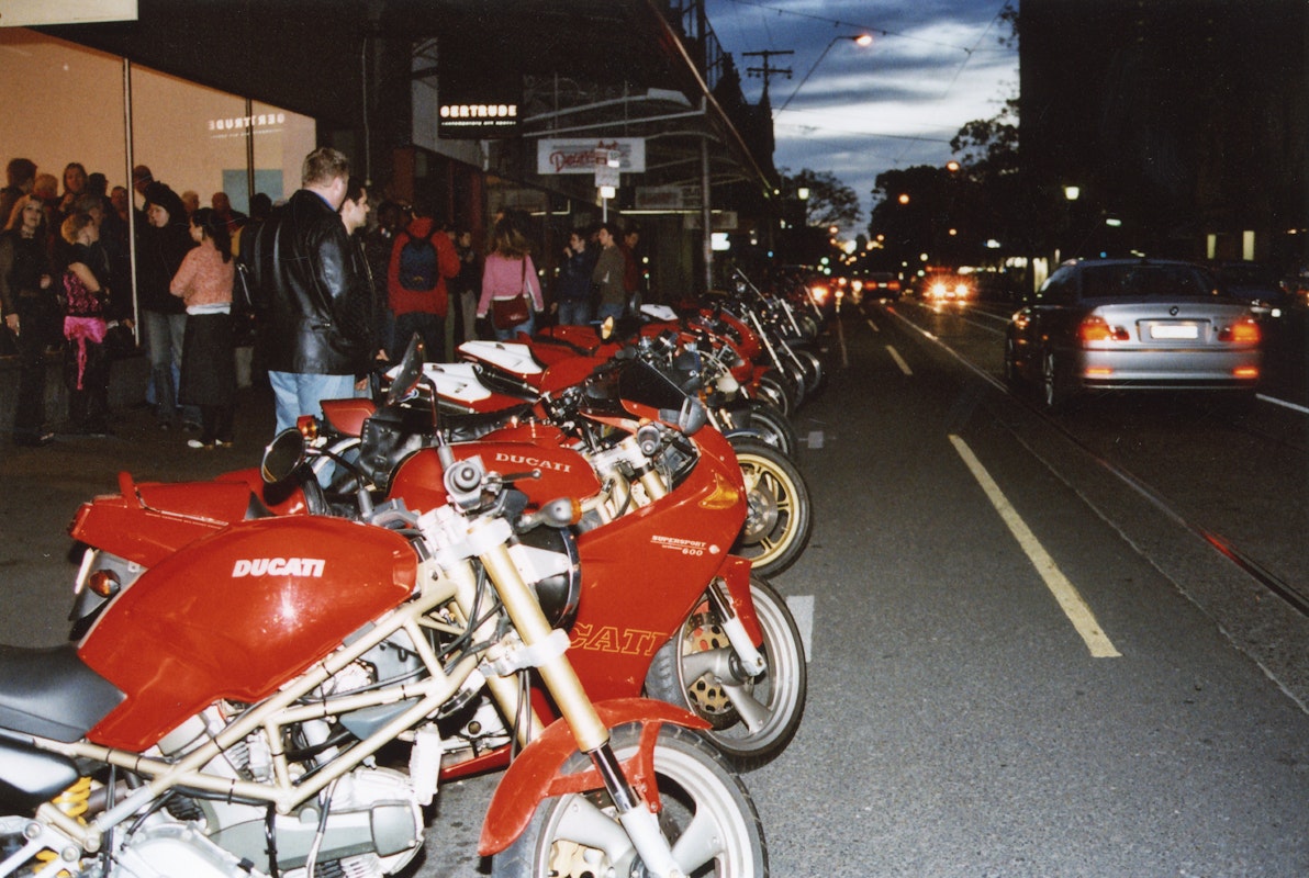 Audiences attend Simone LeAmon, MOTO Showroom, with performance riders from the Moto Guzzi motorcycle club, presented at Gertrude Contemporary Art Spaces, 2003. Courtesy of the artist and the Gertrude Archive.