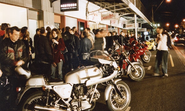 Audiences attend Simone LeAmon, MOTO Showroom, with performance riders from the Moto Guzzi motorcycle club, presented at Gertrude Contemporary Art Spaces, 2003. Courtesy of the artist and the Gertrude Archive.