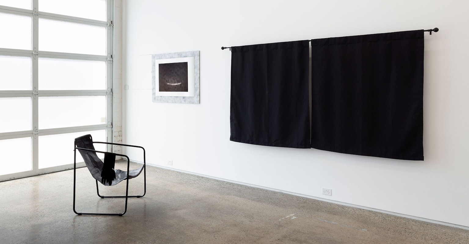 Rohan Schwartz, the Moon smiles back while we look for our shadows, 2024 archival inkjet print on Hahnemuhle PhotoRag Baryta 315gsm paper, Reemay Style 2014 34gsm, adhesives, coloured foam board, Austerlitz Insect Pins; Arthur Nyakuengama, Indoors, 2021, installation view, The Limits of my Language are the Limits of my World, Gertrude Glasshouse, Naarm Melbourne, 2024, leather and steel armchair, shoulder-length, latex gloves, latex polish, curtains, image courtesy and © the artists, photograph: Christian Capurro