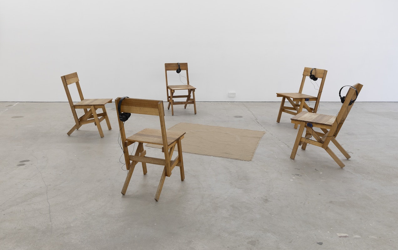 Thea Jones, Autoprogettazione chairs, 2021, Tasmanian oak, linseed oil; Wagga blanket (celtic knot), 2021, hessian, handspun alpaca, blackberry dye; Thea Jones and Bonnie Cummings, Good country girl 2025, spoken word, music, installation view, Bureaucracy of Feelings, Gertrude Contemporary, Naarm Melbourne, 2025, image courtesy and © the artists, photograph: Christian Capurro