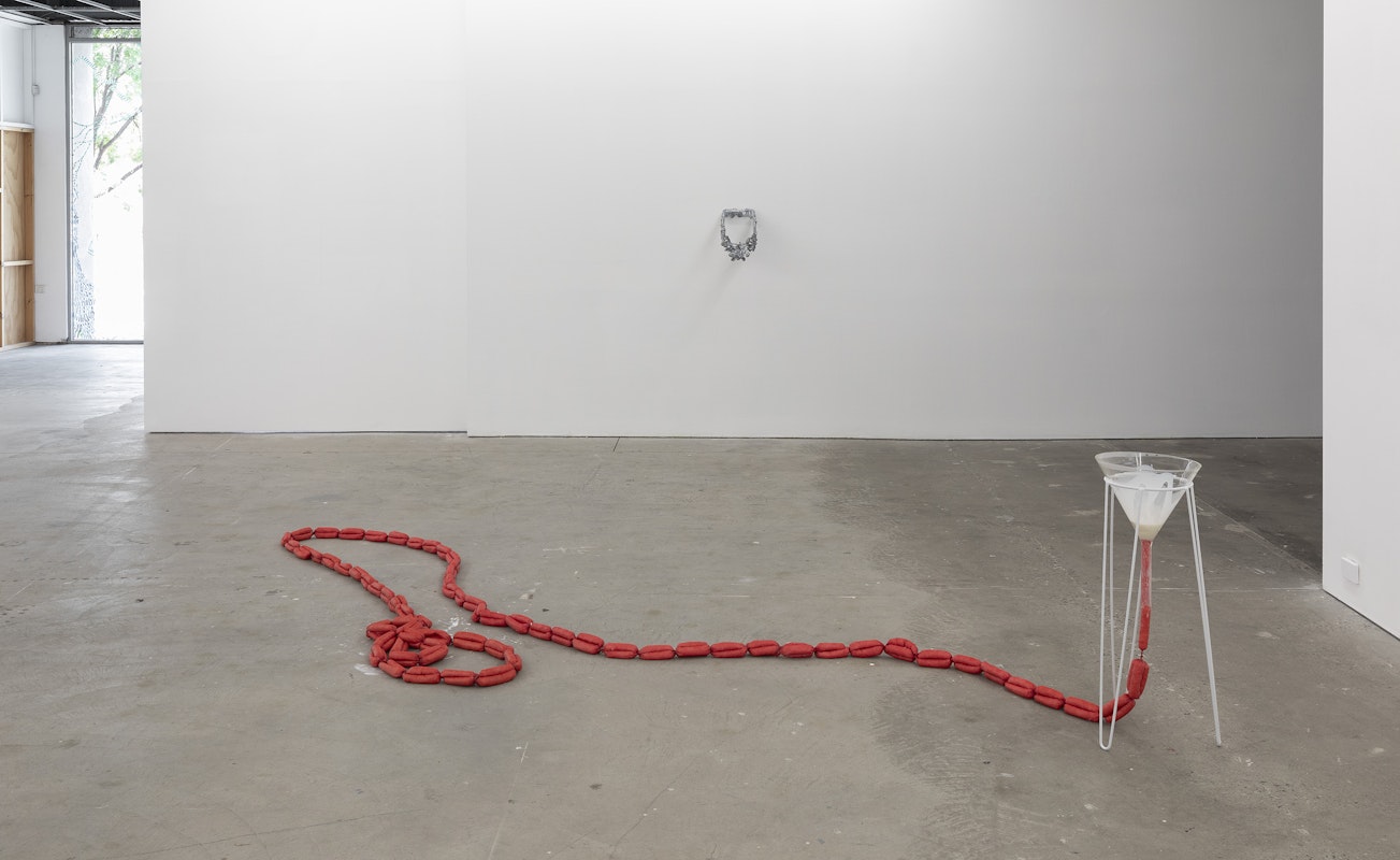 Tara Denny, Ravishing rose, 2025, bronze, patina; Erin Hallyburton, Gut Twist, 2025, collagen hotdog casings, animal shortening, glass funnel, powder-coated aluminium, installation view, Various Small Fires, Gertrude Contemporary, Naarm Melbourne, 2025, image courtesy and © the artists, photograph: Christian Capurro