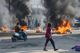 Iraqi protesters are pictured next to burning tires during clashes with police in the city of Nasiriyah on Jan. 10, 2021. (Photo via Getty Images)