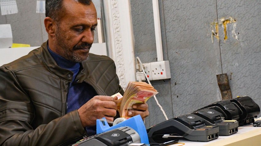 An employee of a currency exchange counter counts bank notes in the southern Iraqi city of Nasiriyah on Dec. 20, 2020. (Photo via Getty Images)