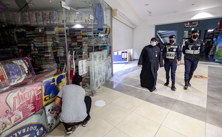 رجال الشرطة يطبقون إجراءات تتعلق بفيروس كوفيد -19 في مدينة الكويت في 10 فبراير/شباط 2021 (الصورة عبر غيتي إيماجز)
