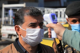 Health officials perform a routine temperature screening in Baghdad, Iraq on Feb. 22, 2021 (Photo via Getty Images)