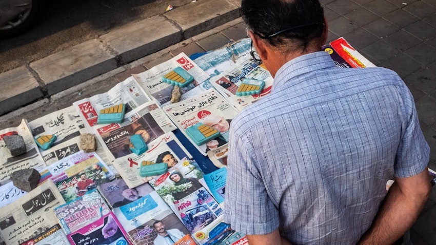 یک مرد ایرانی در حال نگاه به روزنامه‌ها در یک دکه‌ی روزنامه فروشی. تهران، ایران. ۱۶ مرداد ۱۳۹۹ (عکس از سیدجواد میرحسینی از خبرگزاری مهر)