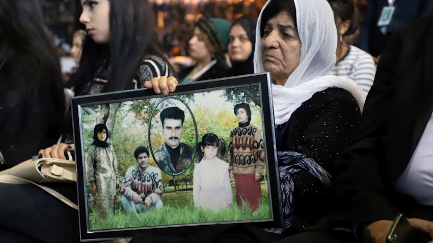 عراقي كردي يحمل صورًا لأقاربه الذين قتلوا في الهجوم بالغاز الكيميائي على حلبجة، على يد القوات الجوية لصدام حسين. (الصورة عبر غيتي إيماجز)